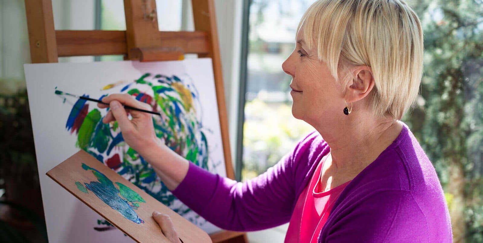 A woman painting at an easel, calm and absorbed