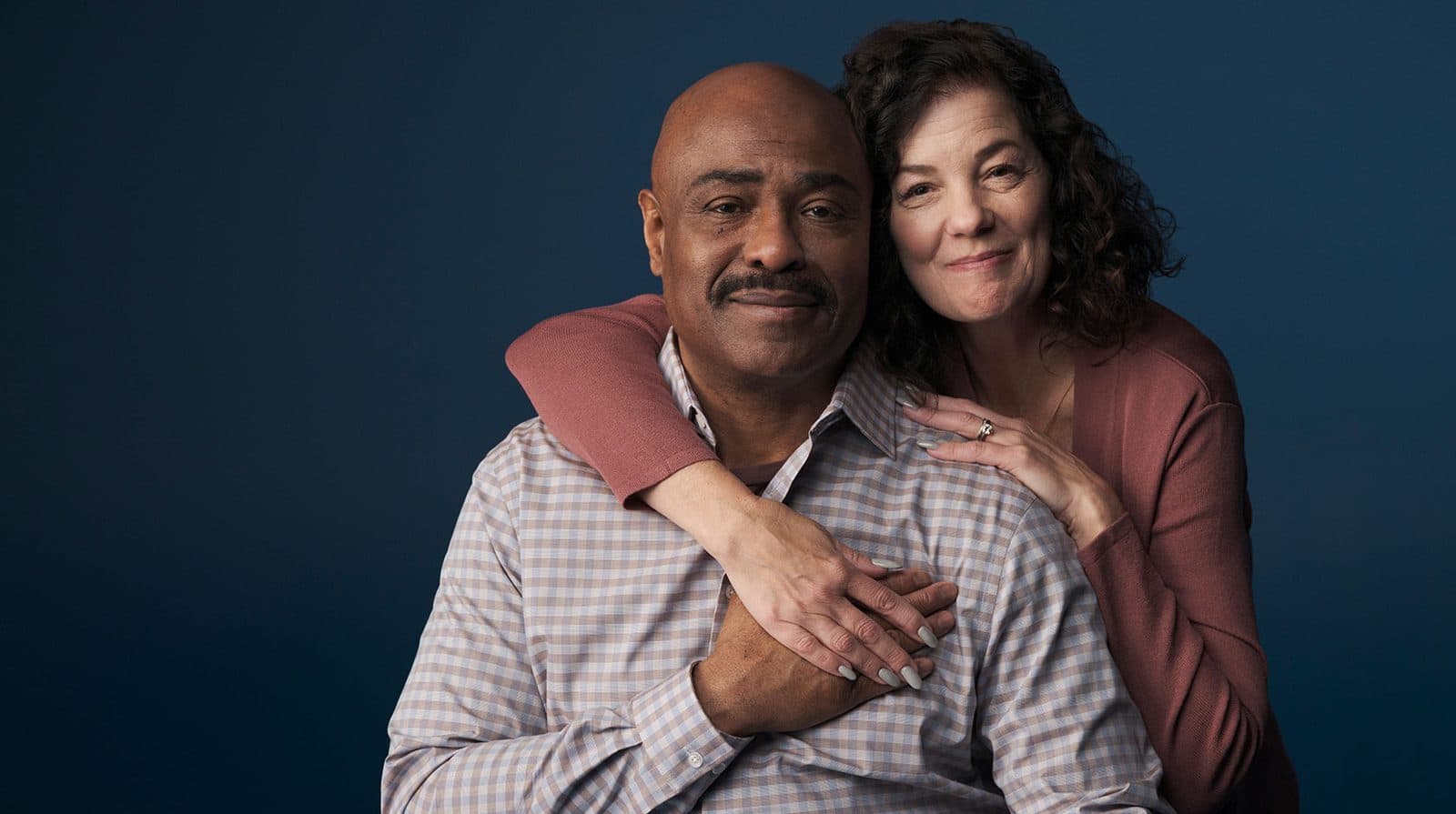 A couple embracing against a deep blue backdrop