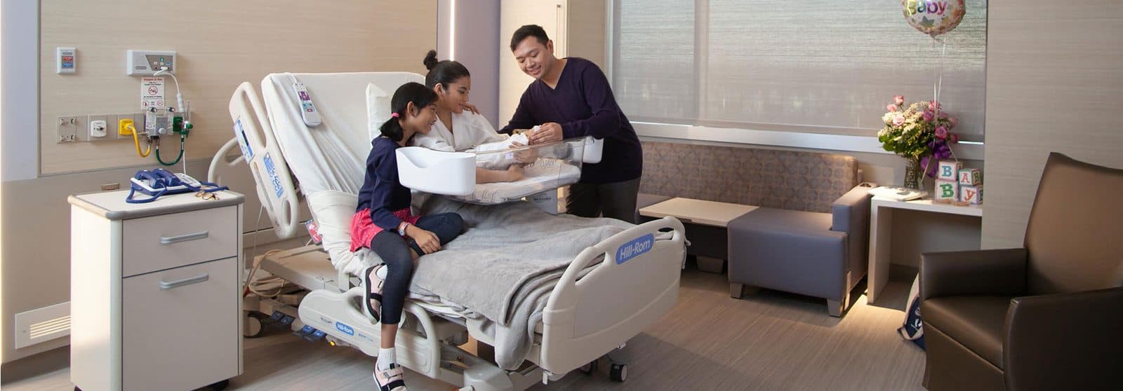 A family with their newborn in a bright hospital birthing suite