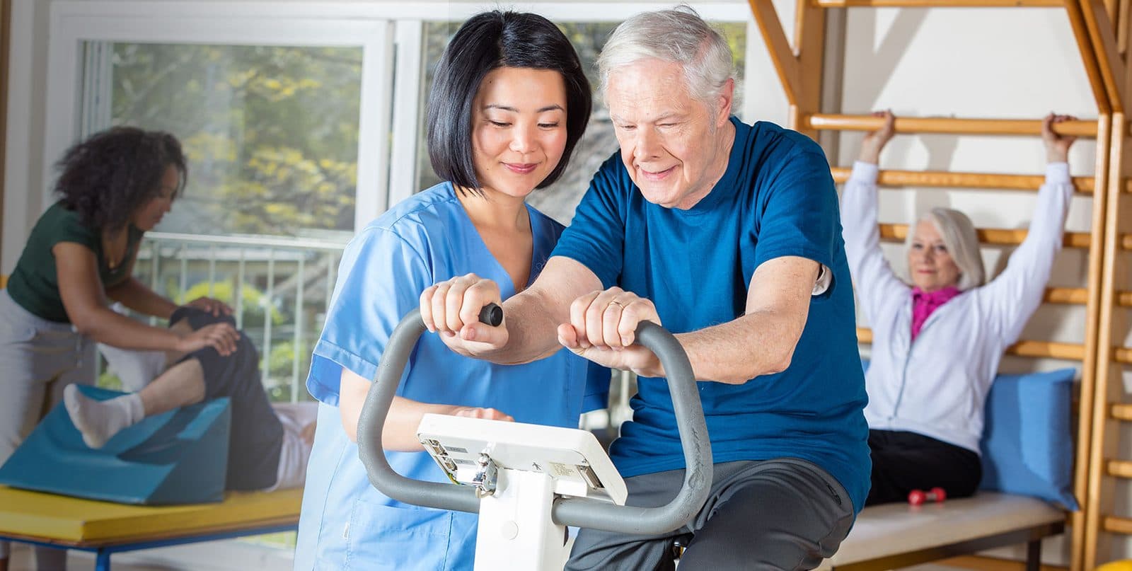 A physical therapist helping a man on a stationary bike in a rehabilitation gym