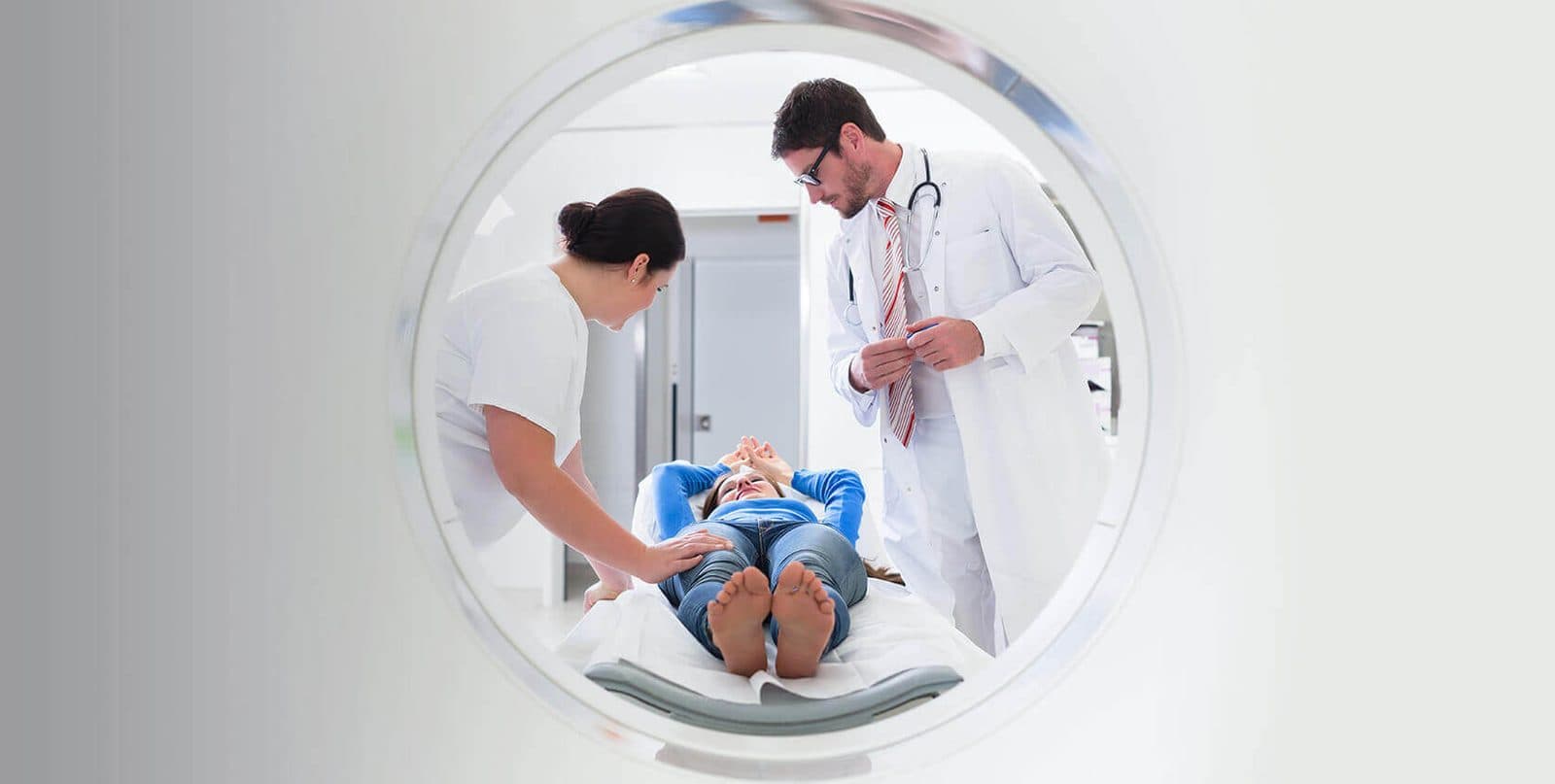A radiologist and nurse caring for a patient inside a bright imaging suite